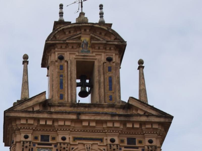 Imagen única del campanario del convento de santa paula, donde se ve tres campanas en el primer nivel, otra en el segundo nivel y una cruz arriba del todo