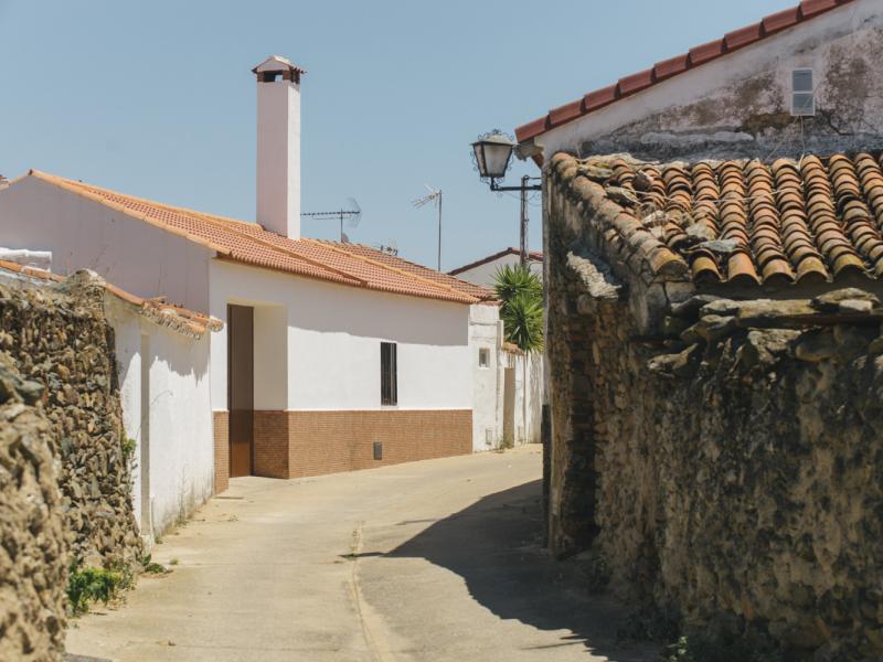 El Madroño. Vista de una calle con muros de piedra y tierra en primer término