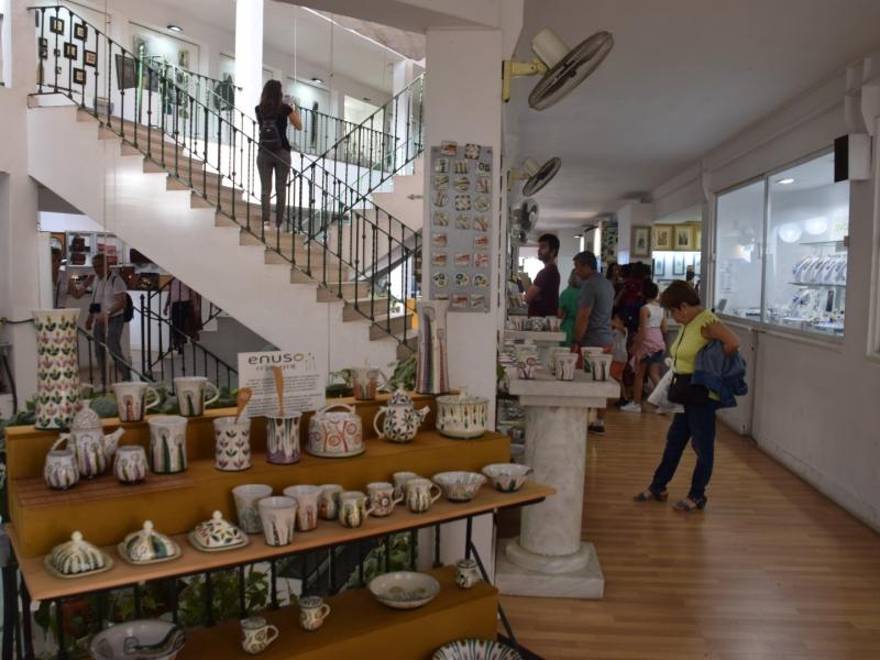 Otra perspectiva de puestos de cerámicas con objetos colgados en la pared en el mercado de artesanía de el postigo y objetos de exposición en el suelo